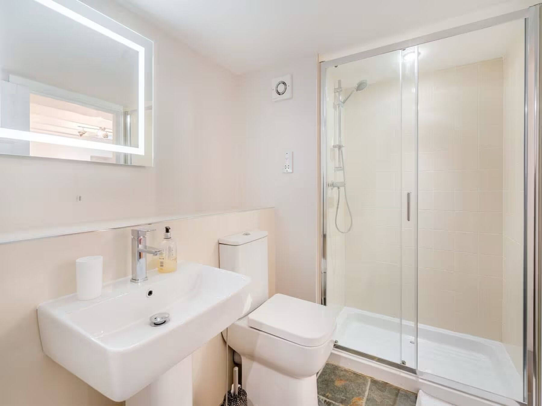 Une salle de bain équipée d’un lavabo, de toilettes et d’une douche à parois de verre.