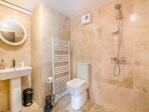 Ein Badezimmer mit Waschbecken, Toilette, Handtuchhalter und Dusche.