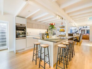 Une cuisine moderne dotée d’un îlot central, de tabourets de bar et d’un coin repas offrant une vue agréable.