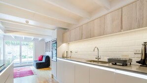 A modern kitchen with white cabinets, a stainless steel sink, and a coffee machine.