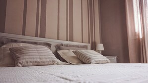 Un lit bien fait, agrémenté d’oreillers à rayures et d’une couverture blanche à motifs.