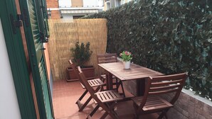 Une terrasse extérieure avec une table et des chaises en bois, une plante en pot et une clôture en bambou.