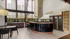 A modern kitchen with a central island, bar stools, a refrigerator, and a wine rack.