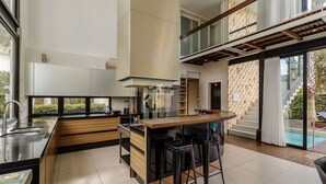 A modern kitchen with a central island, a built-in stove, and a large window overlooking a pool.