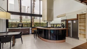 Une cuisine moderne dotée d’un îlot central, de tabourets de bar, d’un réfrigérateur et d’un meuble à vin.