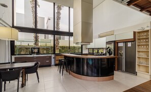 A modern kitchen with a central island, bar stools, a refrigerator, and a wine rack. - House w/ pool 5BR near Jurerê Beach RCA26 (Florianópolis)