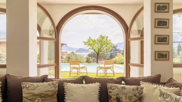 A cozy living room with a large arched window overlooking a pool and garden.