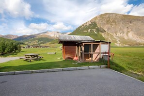 Une cabane rustique avec une table de pique-nique, un petit abri et une vue sur les montagnes en arrière-plan.