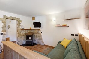 A cozy living room with a stone fireplace, a green sofa, and a wooden bench.