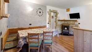 A rustic interior with a stone fireplace, wooden bench, and a table with chairs. - Apartment 'Campacc Baby' with Mountain View, Shared Garden and Wi-Fi (Livigno)