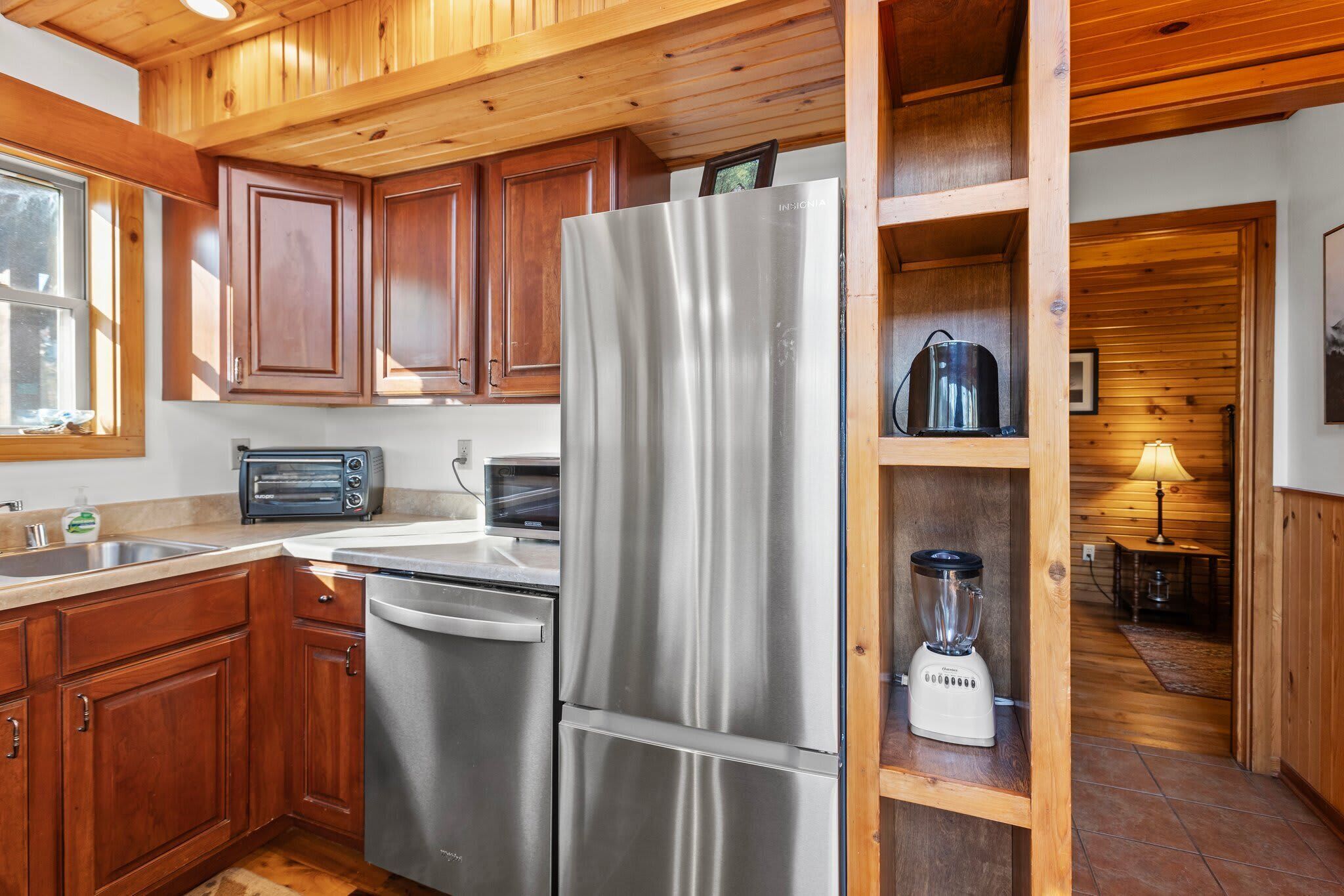 A kitchen with wooden cabinets, stainless steel appliances, a toaster, a microwave, and a blender.