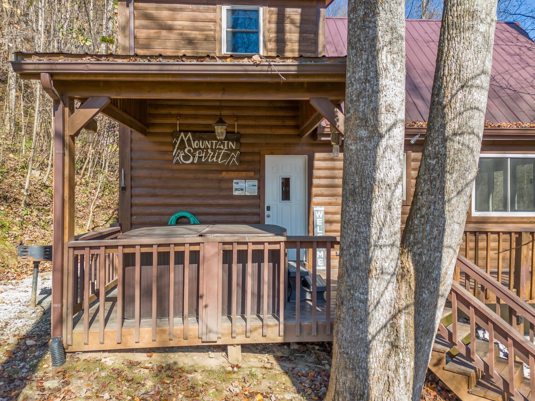 A wooden cabin with a porch, a sign reading "Mountain Spirit", and a welcome sign.