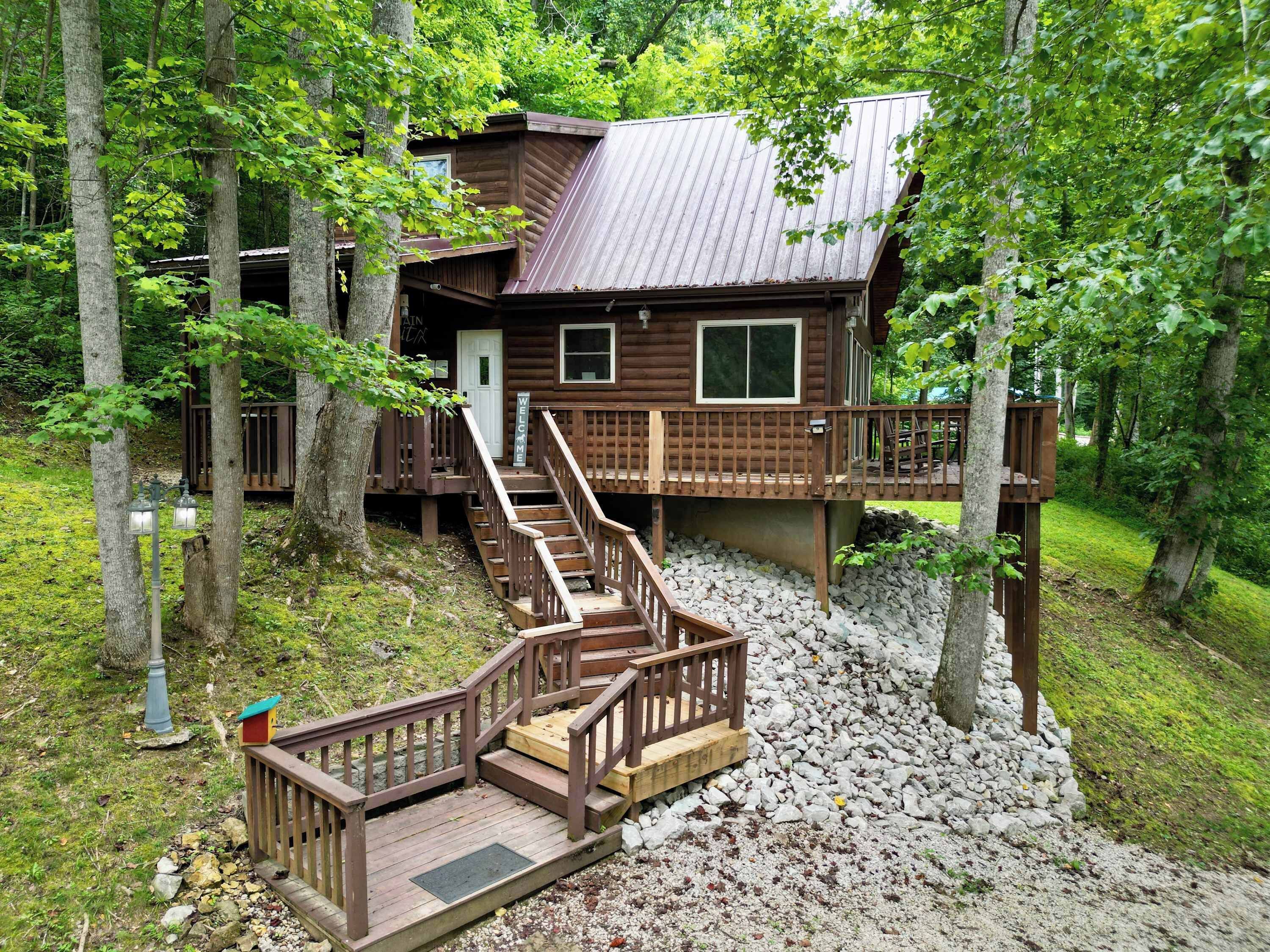Une cabane dotée d’une terrasse en bois, d’un escalier et d’un toit en métal.