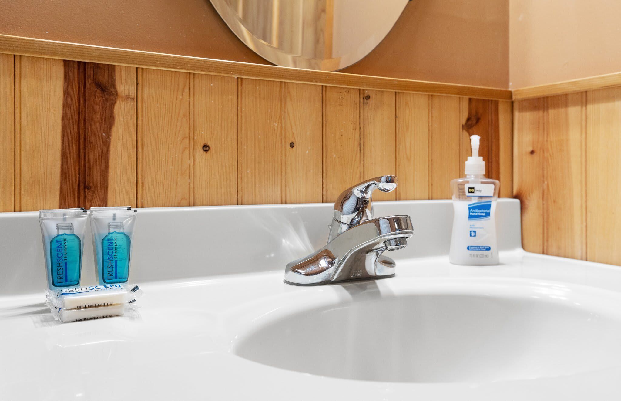 En vask med kromarmatur, to flasker FreshSCENT shampoo og en flaske antibakteriel håndsprit.