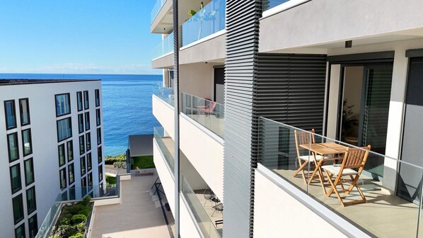 Un appartement moderne doté d’un balcon avec vue sur la mer, comprenant un coin repas avec des meubles en bois.