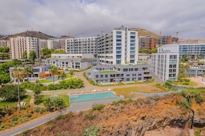 A modern hotel complex with multiple high-rise buildings, a swimming pool, and landscaped gardens.