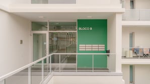 A multi-level building with a glass railing, a green wall labeled "BLOCO B," and a staircase. - FLH Funchal City View at Quinta da Nogueira Reside (Funchal)