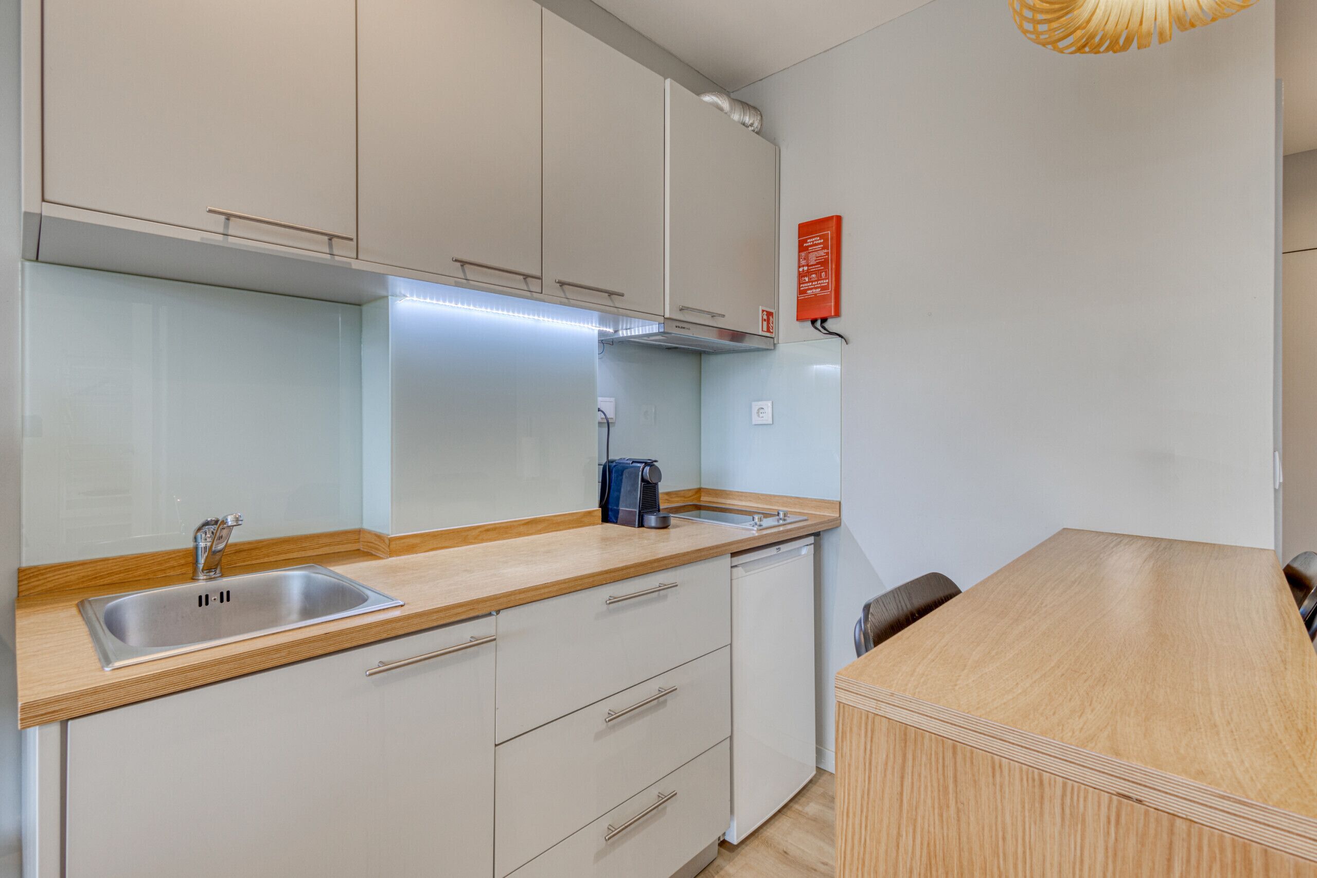 Een moderne keuken met witte kasten, een roestvrijstalen spoelbak en een houten aanrecht.