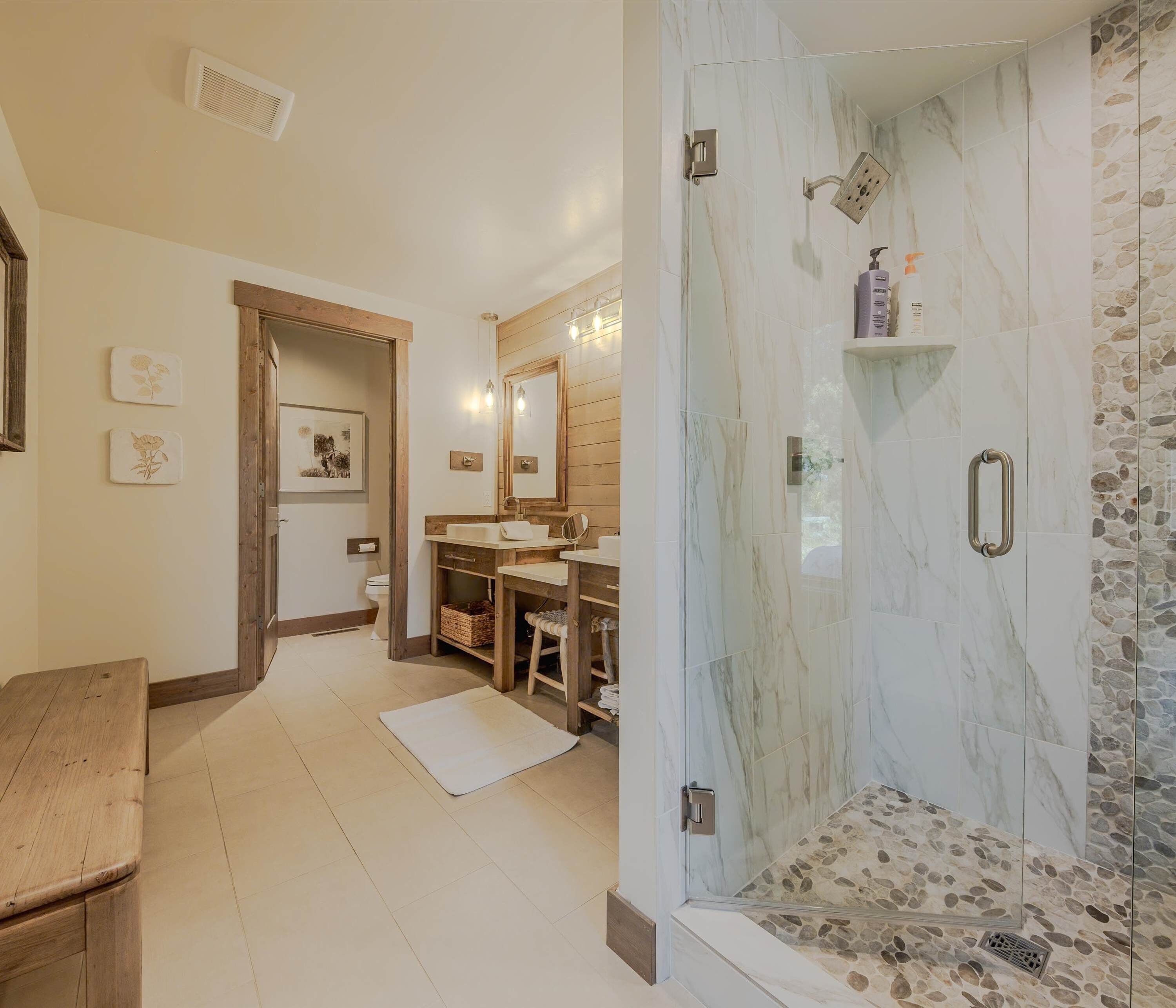 Une salle de bain avec une douche, un meuble-lavabo et un banc en bois.
