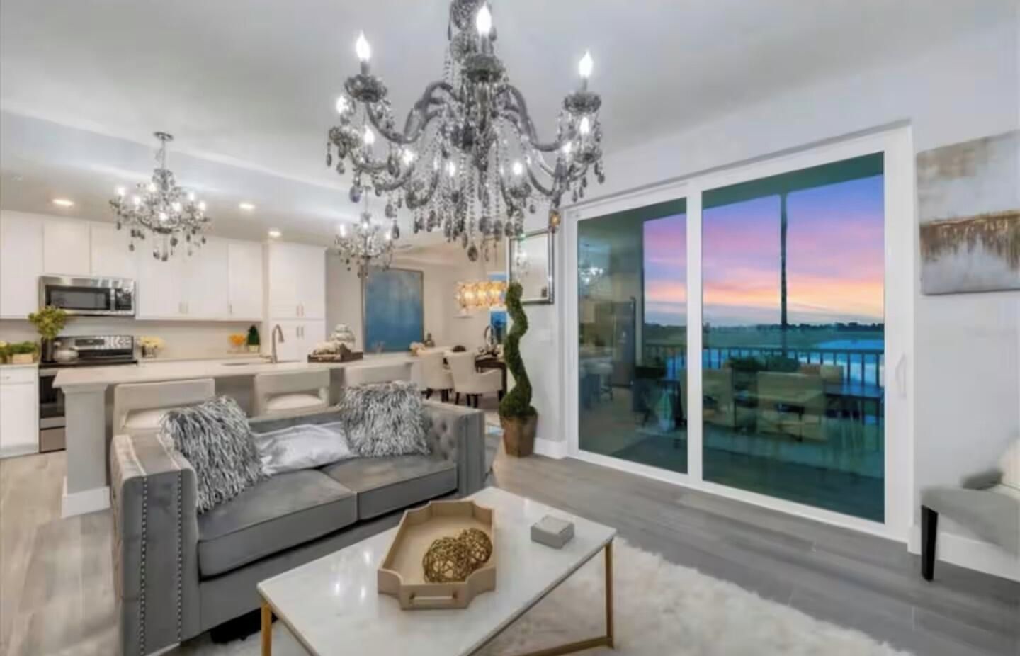 A modern living room with a grey sofa, a coffee table, and a chandelier.
