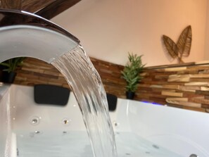 Un baño de diseño moderno, con cabina de ducha de vidrio y pared de madera decorada con motivos vegetales.