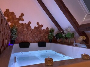 Ein Wellnessbereich mit Holzwand, Badewanne und diversen Pflanzen.