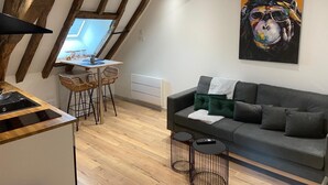 A modern living space with exposed wooden beams, a dining area with a table and chairs, a sofa, and a painting on the wall. - Love Room downtown with Jacuzzi (Bourges)
