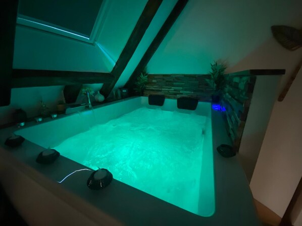 A hot tub with a stone wall backdrop and a window above it. - Love Room with Jacuzzi in the city center (Bourges)