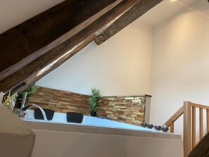 A kitchen with a stone backsplash, a sink, and a wooden ceiling beam. - Love Room with Jacuzzi in the city center (Bourges)