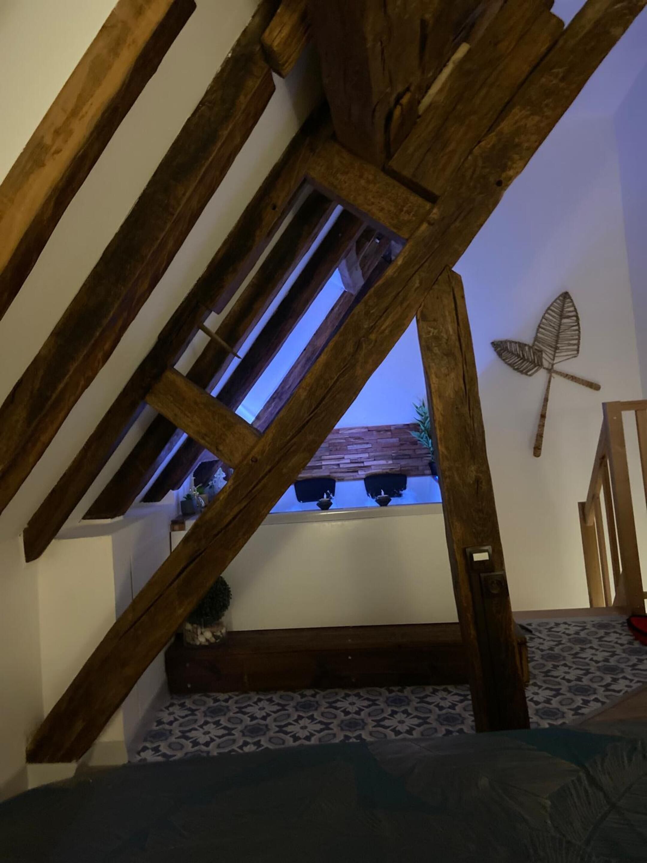 Una habitación con vigas de madera a la vista, techo inclinado y suelo con diseño.