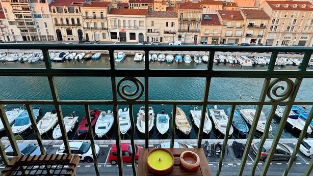 Uma varanda com vista para um porto de iates e edifícios da cidade.