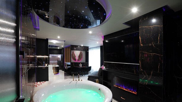 Ein modernes Badezimmer mit einer großen Badewanne, einem Kamin und einer Gestaltung des Deckenfonds wie einen Sternenhimmel.