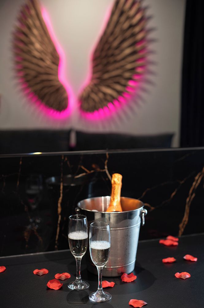 Una zona de bar con copas de champán, un cubo de champán y pétalos de rosa sobre una superficie de mármol.