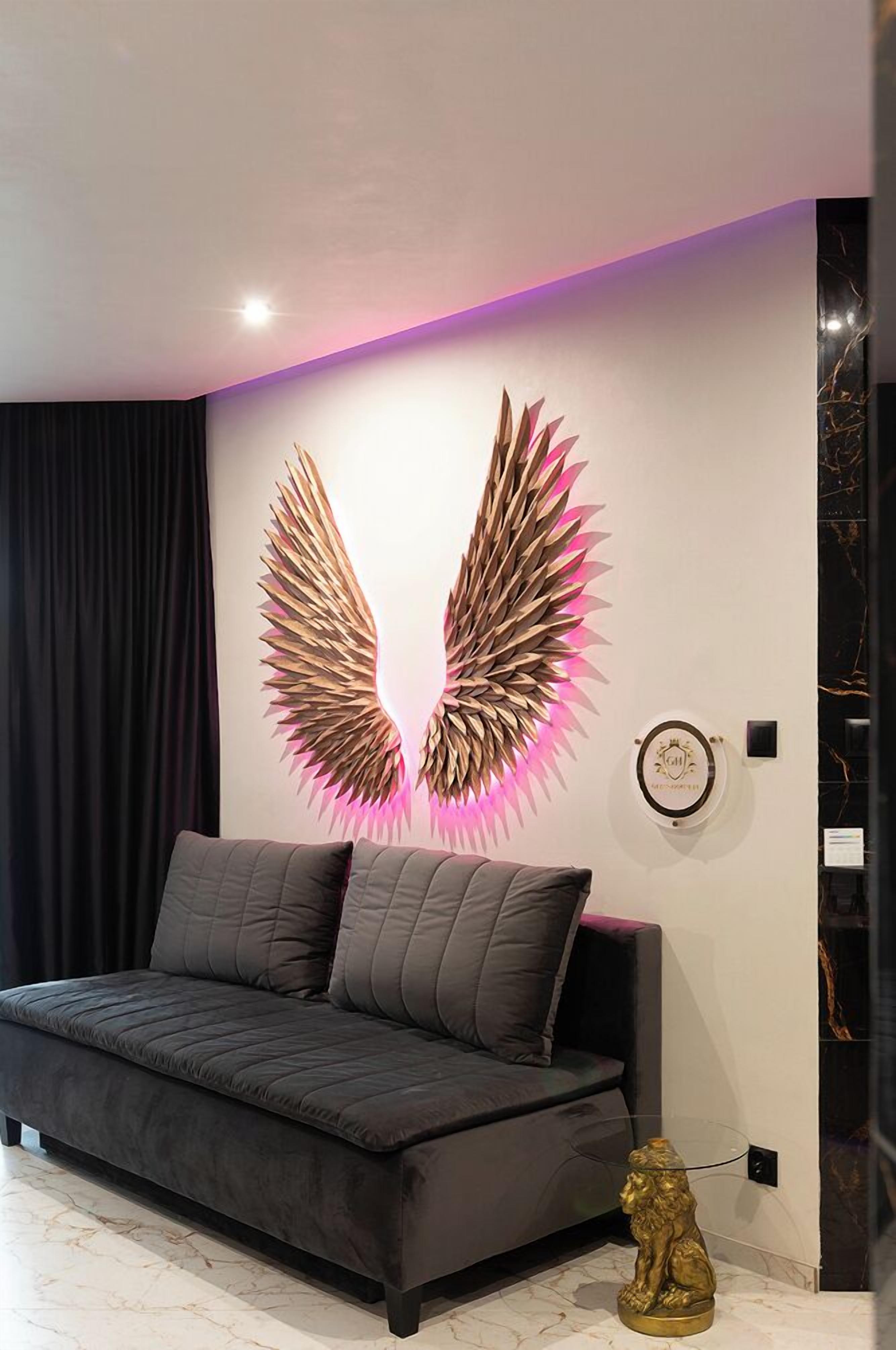 Un salón moderno con un sofá oscuro, una pieza decorativa en la pared y una pequeña estatua dorada.