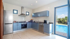 A modern kitchen with a built-in oven, microwave, and coffee maker, and a large sliding glass door leading to a pool.