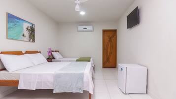 Una habitación de hotel con dos camas, ventilador de techo, aire acondicionado, televisor y refrigerador.