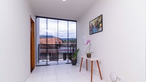 A spacious balcony with large windows, a potted orchid, and a painting on the wall. - Pousada Lagoa Azul (Paraty)