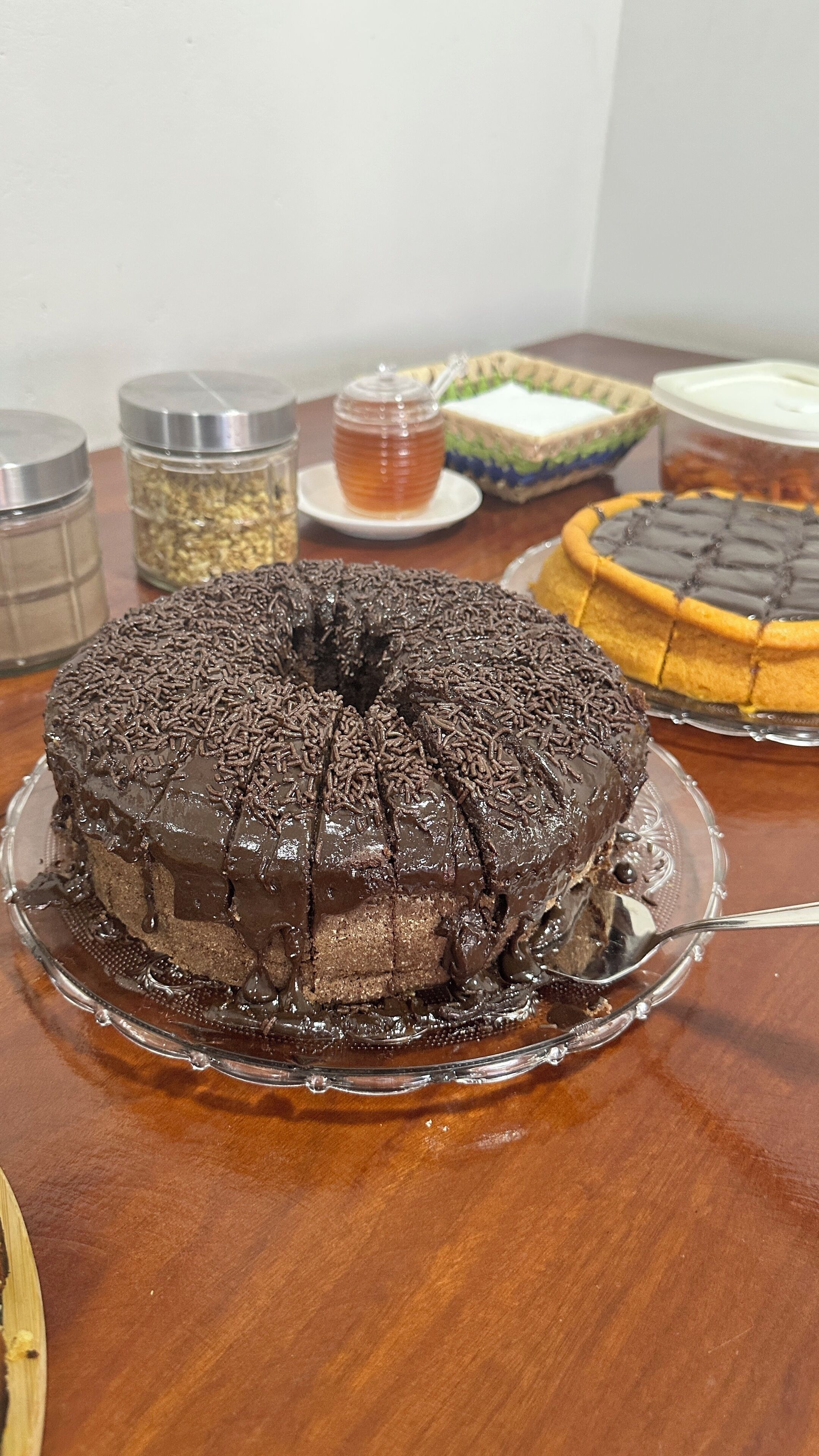 Un gâteau au chocolat décoré de vermicelles de chocolat, présenté sur une assiette en verre.