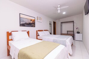 A hotel room with two single beds, a ceiling fan, a TV, and a framed picture of a beach scene. - Pousada Lagoa Azul (Paraty)