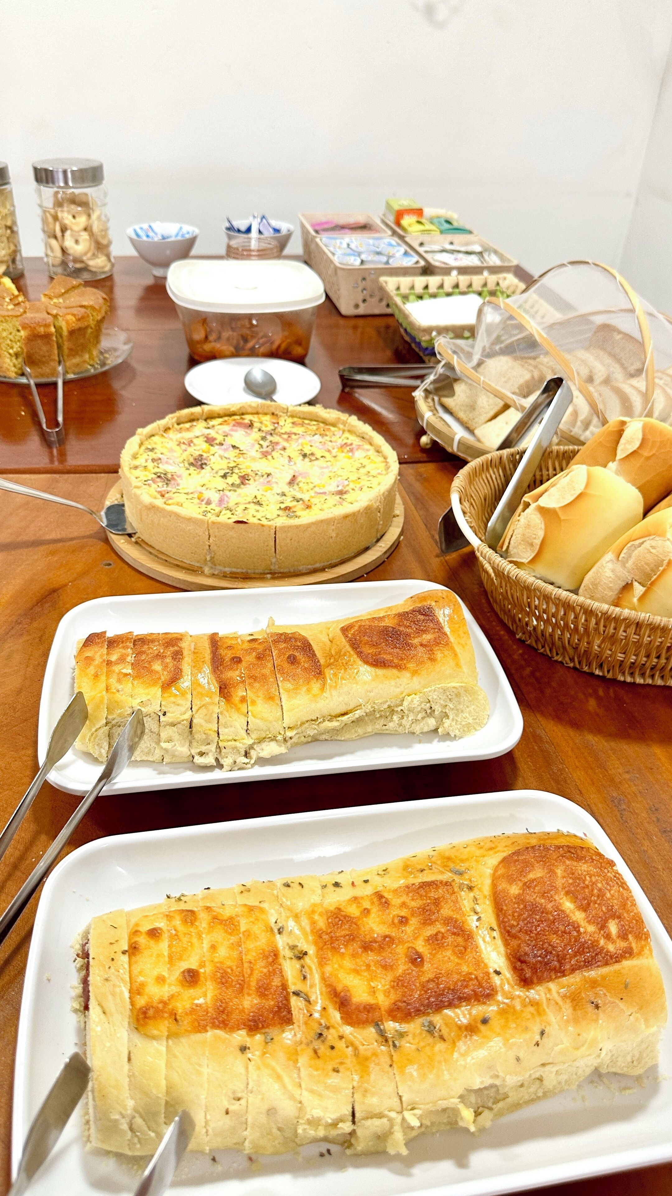 Una mesa de bufé con diversos alimentos, incluyendo una quiche, pan y pasteles.