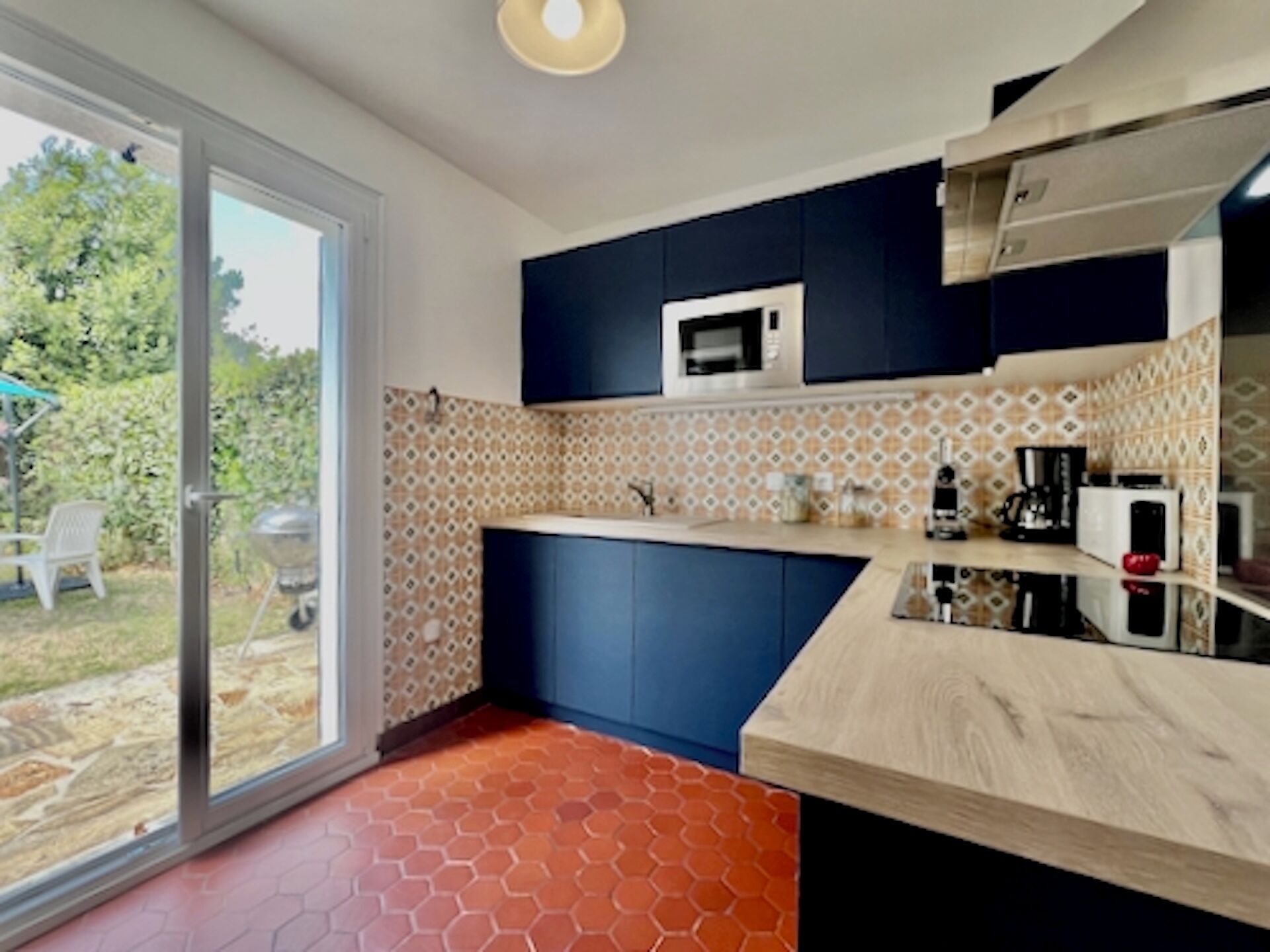 A modern kitchen with blue cabinets, a microwave, and a coffee maker.