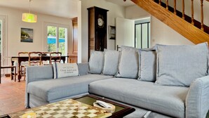 A living room with a grey sofa, a coffee table with a chessboard, a wooden staircase, and a clock on the wall. - Lec'h Mat-Port Haliguen Quiberon-Wifi-6p-linen included (Quiberon)