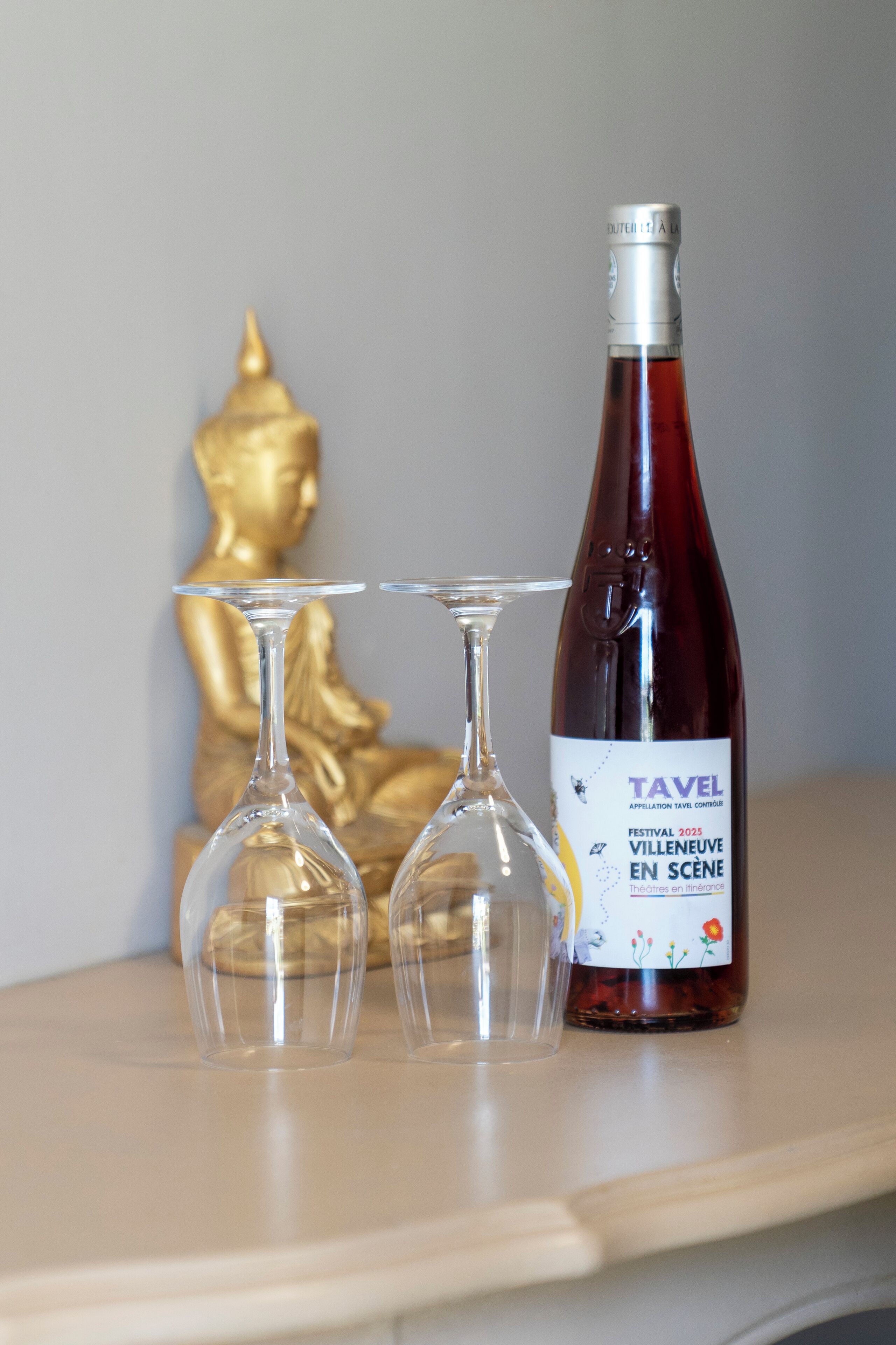 Une bouteille de vin de Tavel et deux verres à vin vides sur une table.