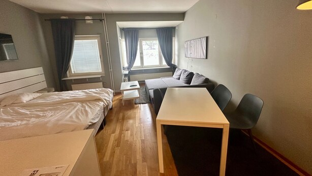 Une chambre d’hôtel avec un lit, une petite table, un canapé et une fenêtre avec des rideaux.