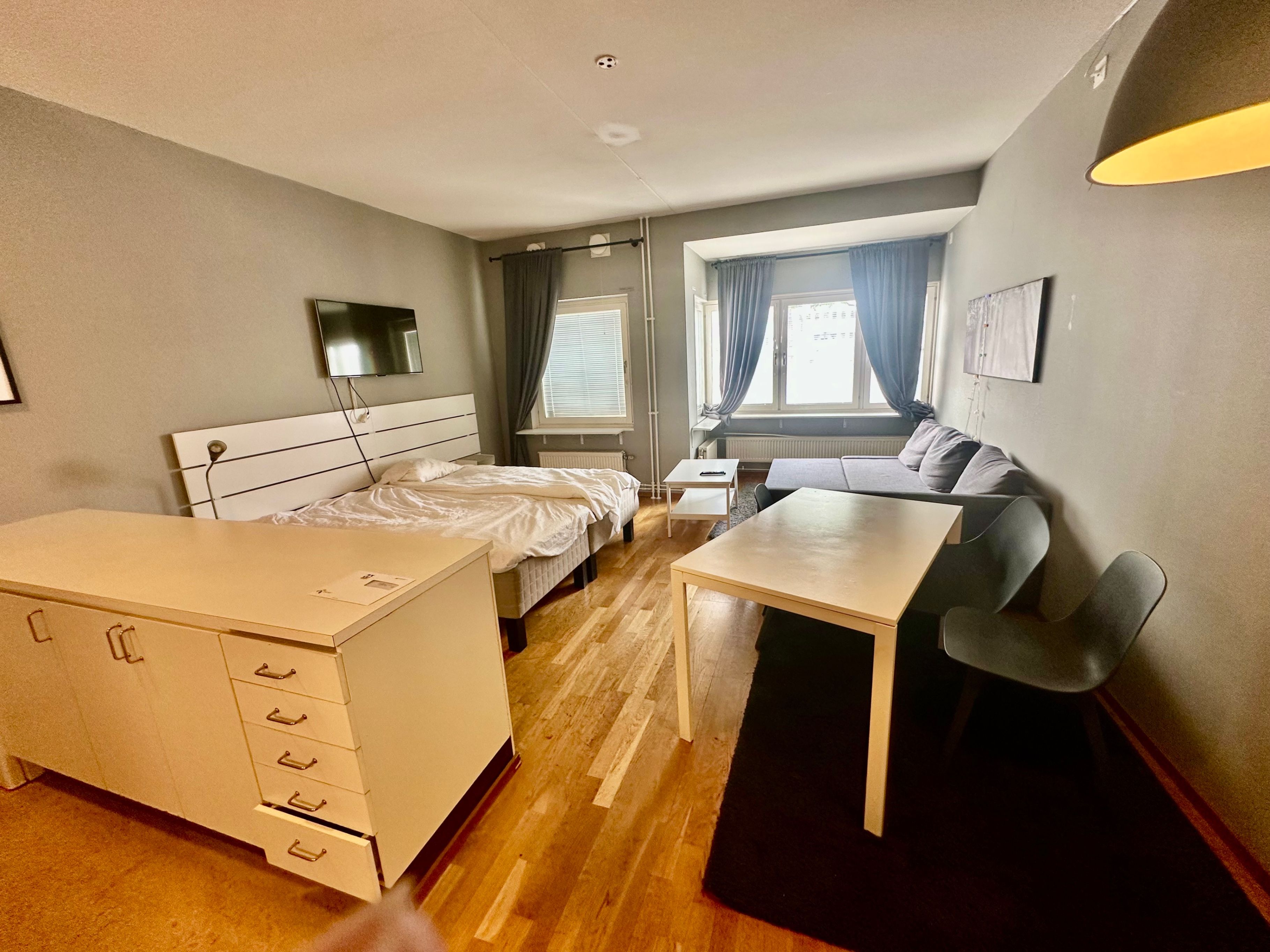 Une chambre d’hôtel avec un lit, un bureau, une chaise, un canapé et une fenêtre avec des rideaux.