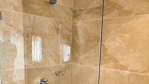 A walk-in shower with a glass door, marble walls, and a handheld showerhead. - Welcomheritage Kasmanda Palace (Dehradun)