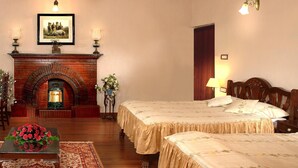 Camera d'albergo con camino, due letti, pavimento in legno e tavolo da pranzo con composizione floreale.