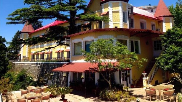 Un grande edificio a più piani con un tetto rosso caratteristico e pareti gialle, con un balcone arredato.