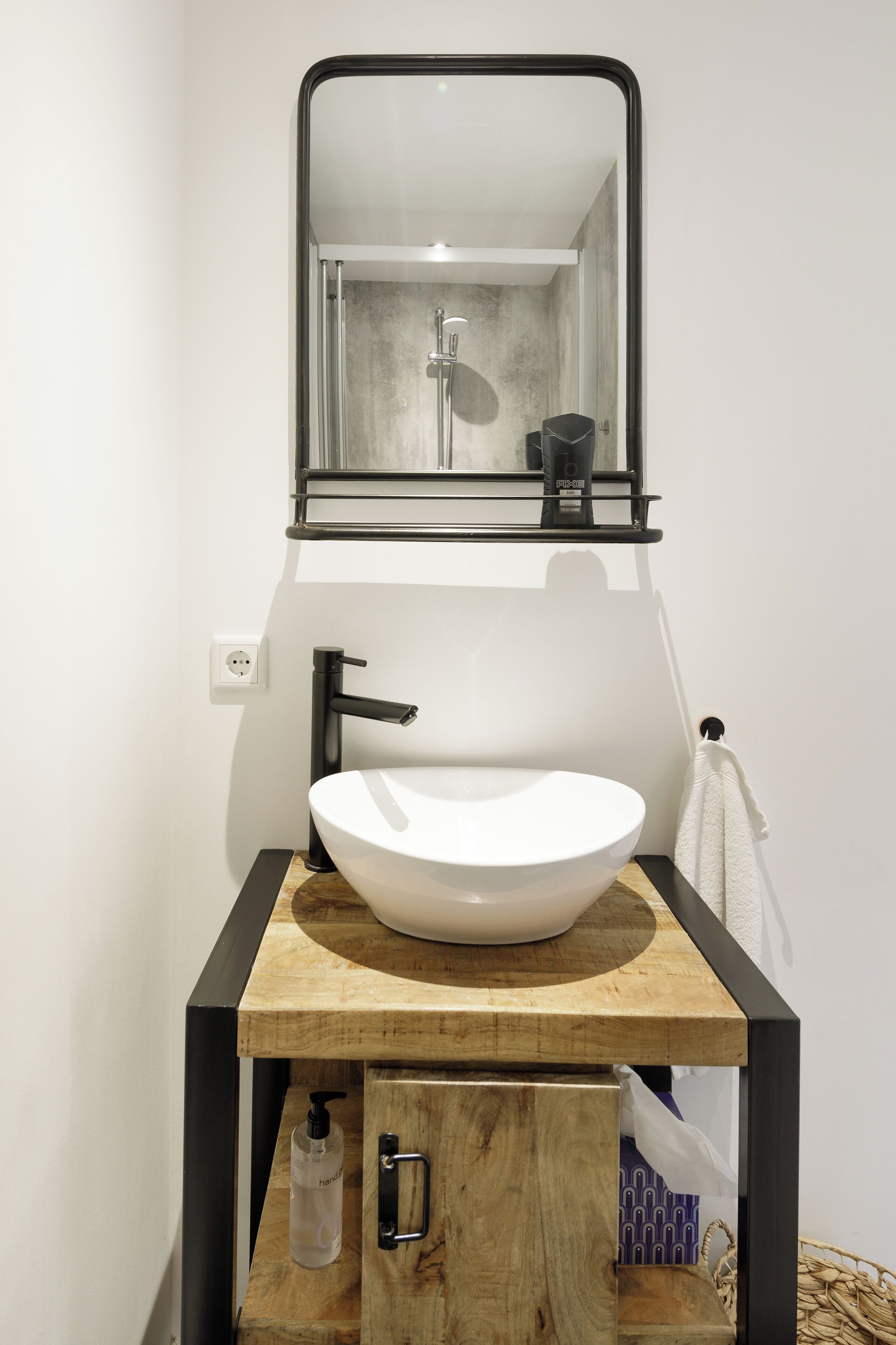 Un bagno con lavandino bianco, rubinetto nero e uno specchio sopra.