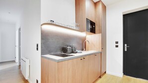 A compact kitchen with wooden cabinets, a microwave, and a toaster.